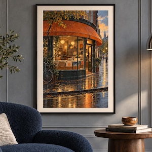 May include: A framed wall art print depicting a street-level view of a corner shop with a large orange awning, glowing interior lights, and a bicycle parked outside on a wet, reflective pavement during a sunset or twilight hour.