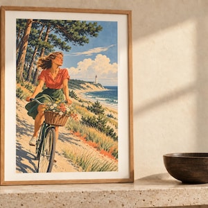 May include: A framed art print featuring a person riding a bicycle with a basket of flowers along a sandy coastal path. The scene includes pine trees, a distant lighthouse, and a blue ocean under a bright sky with white clouds.
