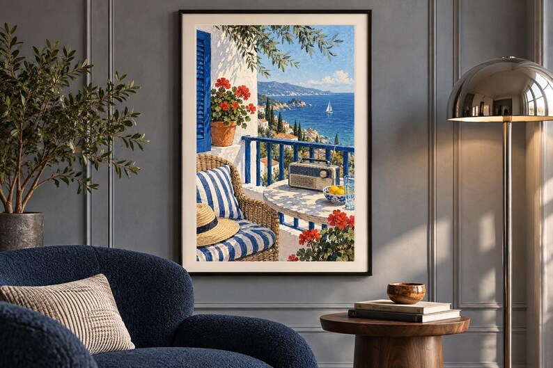 Puede incluir: Una impresi&oacute;n de arte mural enmarcada que representa una escena de balc&oacute;n mediterr&aacute;neo con una silla de mimbre con cojines a rayas azules y blancas, un sombrero de paja, una radio en una mesa redonda, geranios rojos y vista al mar y la costa.