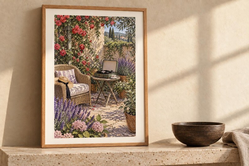 Puede incluir: Una l&aacute;mina de arte enmarcada que muestra una escena de patio soleado con una silla de mimbre, una mesa redonda peque&ntilde;a con un tocadiscos, rosas trepadoras rosas, lavanda morada y plantas en macetas contra un muro de piedra.
