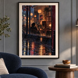 Puede incluir: Una impresi&oacute;n de arte mural enmarcada que representa una escena nocturna lluviosa vista a trav&eacute;s de una ventana. La obra muestra a una persona sentada dentro de un caf&eacute; c&aacute;lido y tenuemente iluminado con luces colgantes brillantes.