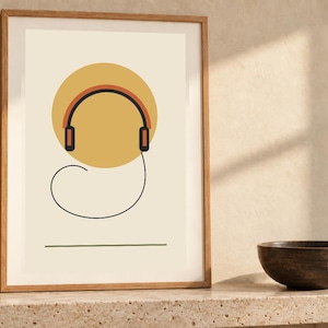 May include: A framed wall art print featuring a minimalist graphic of black and orange headphones centered over a large yellow circle on a cream background, with a thin black line forming a loop below and a straight horizontal line at the base.