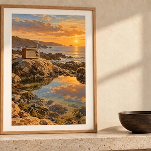 May include: A framed vertical wall art print featuring a landscape of a rocky coastline at sunset. A vintage-style radio sits on a large rock overlooking the ocean, with the golden sun reflecting in a tide pool in the foreground.