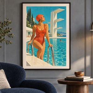 May include: A framed wall art print depicting a person in a red swimsuit and matching swim cap standing at the edge of a bright blue swimming pool. A tall white diving platform stands in the background under a clear sky with cypress trees.