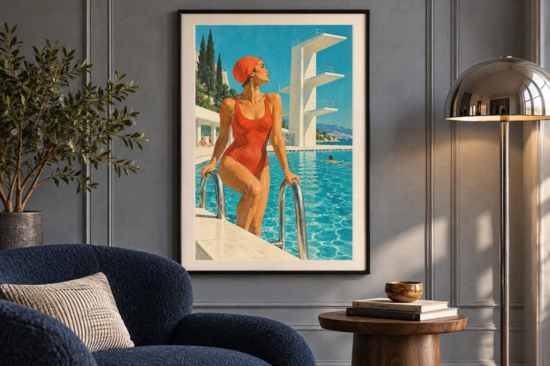 May include: A framed wall art print depicting a person in a red swimsuit and matching swim cap standing at the edge of a bright blue swimming pool. A tall white diving platform stands in the background under a clear sky with cypress trees.