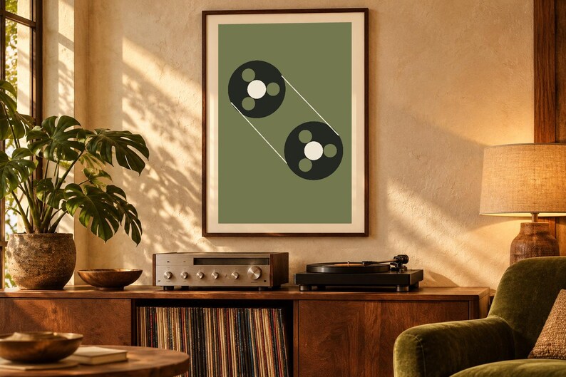 May include: A framed wall art print featuring a sage green background with a graphic illustration of two black circular tape reels connected by thin white lines, each reel containing three small circles in white and green.