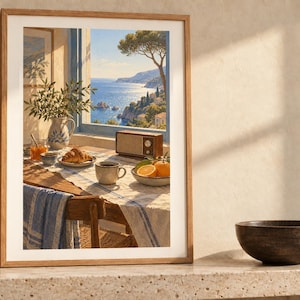 May include: A framed wall art print depicting a sunlit breakfast table by an open window overlooking a coastal sea view. The scene includes a croissant, a cup of coffee, oranges, a vintage radio, and a pitcher with greenery on a table.
