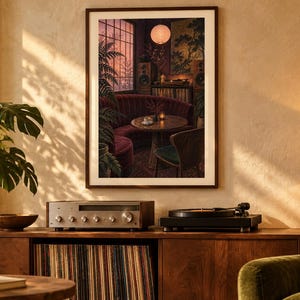 May include: A framed vertical wall art print depicting a cozy, dimly lit lounge interior with a curved burgundy booth, a round wooden table, a record player, and a warm glowing paper lantern, all set against a window with a sunset view.