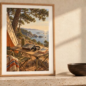 May include: A framed wall art print depicting a camping scene with a tent, a folding table, a thermos, a radio, headphones, and a book overlooking a coastal landscape with pine trees and the ocean under a warm, golden sunset sky.