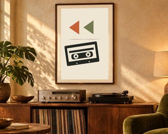 May include: A framed wall art print featuring a black cassette tape graphic centered below a small orange triangle and a green triangle on a cream background. The print is displayed in a dark brown frame hanging on a textured wall.