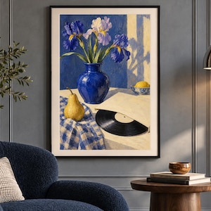 May include: A framed wall art print depicting a still life scene with a blue vase containing purple and white irises, a yellow pear, a black vinyl record in a paper sleeve, and a small bowl with a lemon, all set on a blue and white checkered cloth.