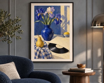 May include: A framed wall art print depicting a still life scene with a blue vase containing purple and white irises, a yellow pear, a black vinyl record in a paper sleeve, and a small bowl with a lemon, all set on a blue and white checkered cloth.