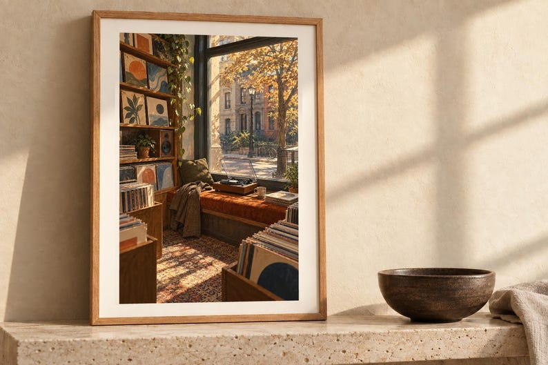 May include: A framed art print depicting a cozy room interior with a window view of an autumn street, wooden shelves filled with records and framed art, a record player on a window seat, and a patterned rug in warm, golden sunlight.