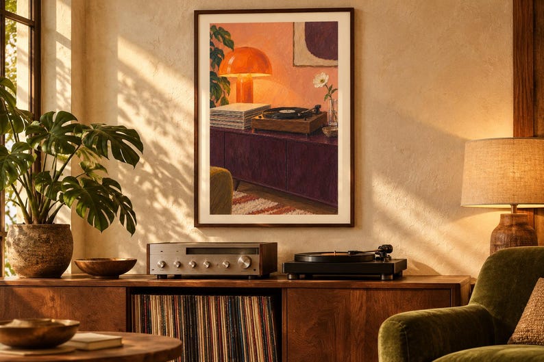 May include: A framed wall art print depicting a warm interior scene with a record player, a stack of vinyl records, a bright orange mushroom lamp, and a single white flower in a glass vase, all set upon a dark purple cabinet against a pink wall.