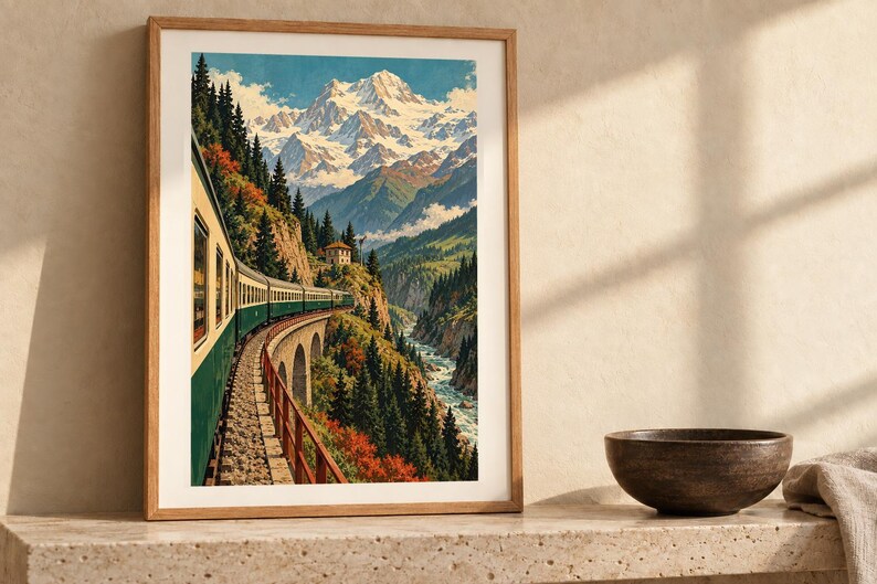 May include: A framed vertical wall art print depicting a green and cream train traveling along a stone viaduct through a mountain valley. The scene features snow-capped peaks, dense evergreen forests, and a river flowing below the tracks.