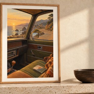 Puede incluir: Una l&aacute;mina de arte enmarcada que representa el interior de un coche antiguo con vistas a una carretera costera al atardecer. La escena muestra un asiento tapizado en verde, una palanca de cambios de madera y el mar y acantilados.