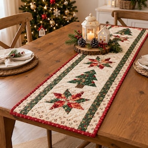 May include: A quilted table runner featuring a repeating pattern of green Christmas trees and red and green star motifs on a cream background, bordered by red and green fabric strips. The runner is laid flat on a wooden dining table.