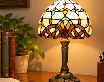 Tafellamp van gebrandschilderd glas met krulpatroon in amberblauw of paars, met een koepelvormige kap in Tiffany-stijl en een sierlijke bronzen voet.