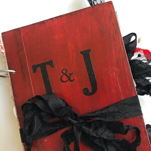 May include: Red wooden journal with a black ribbon and bow. The cover has the initials "T & J" in black paint.