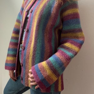 以下が含まれることがあります： ボタン留めのストライプカーディガン。カーディガンは柔らかなニット生地で作られており、パープル、ブルー、グリーン、イエローなど、さまざまな色を使用しています。