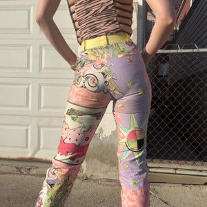 Pode incluir: Uma cal&ccedil;a de cintura alta com um design de patchwork colorido. A cal&ccedil;a &eacute; feita de um tecido leve e tem um caimento solto. O design apresenta uma variedade de padr&otilde;es, incluindo flores, estrelas e formas geom&eacute;tricas. A cal&ccedil;a &eacute; uma mistura vibrante de rosa, roxo, amarelo e verde.
