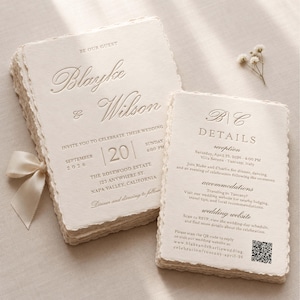 May include: A stack of cream-colored wedding invitation cards with deckled edges and embossed text reading Blayke & Wilson, September 20, 2026, at The Rosewood Estate, Napa Valley, California, accompanied by a matching details card with a QR code.