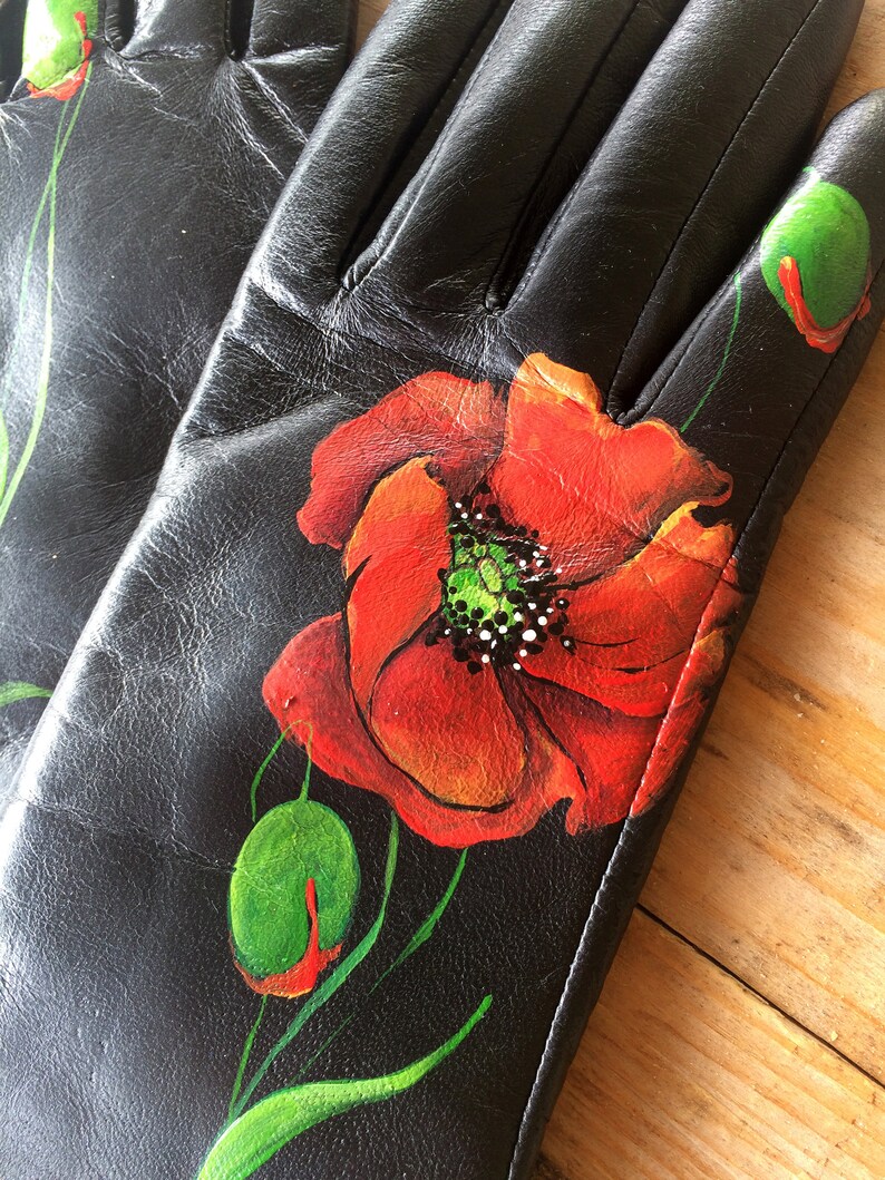 K&ouml;nnte beinhalten: Schwarze Lederhandschuhe mit handbemaltem Mohnblumenmuster. Die Blume ist rot mit gr&uuml;nem Zentrum und gr&uuml;nen Bl&auml;ttern.