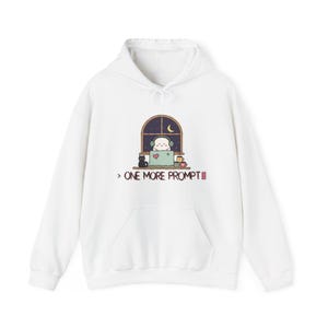 May include: A white hooded sweatshirt featuring a graphic of a character wearing headphones at a laptop in front of a window at night, with a black cat and mugs on the desk. Below the graphic, the text reads: > ONE MORE PROMPT with a cursor block.