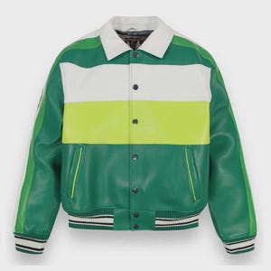 Puede incluir: Una chaqueta tipo varsity de bloques de color con cuello blanco, panel superior blanco, franja central verde lima y sección inferior verde oscuro. La prenda cuenta con mangas largas, cierre frontal de botones a presión y puños acanalados a rayas.