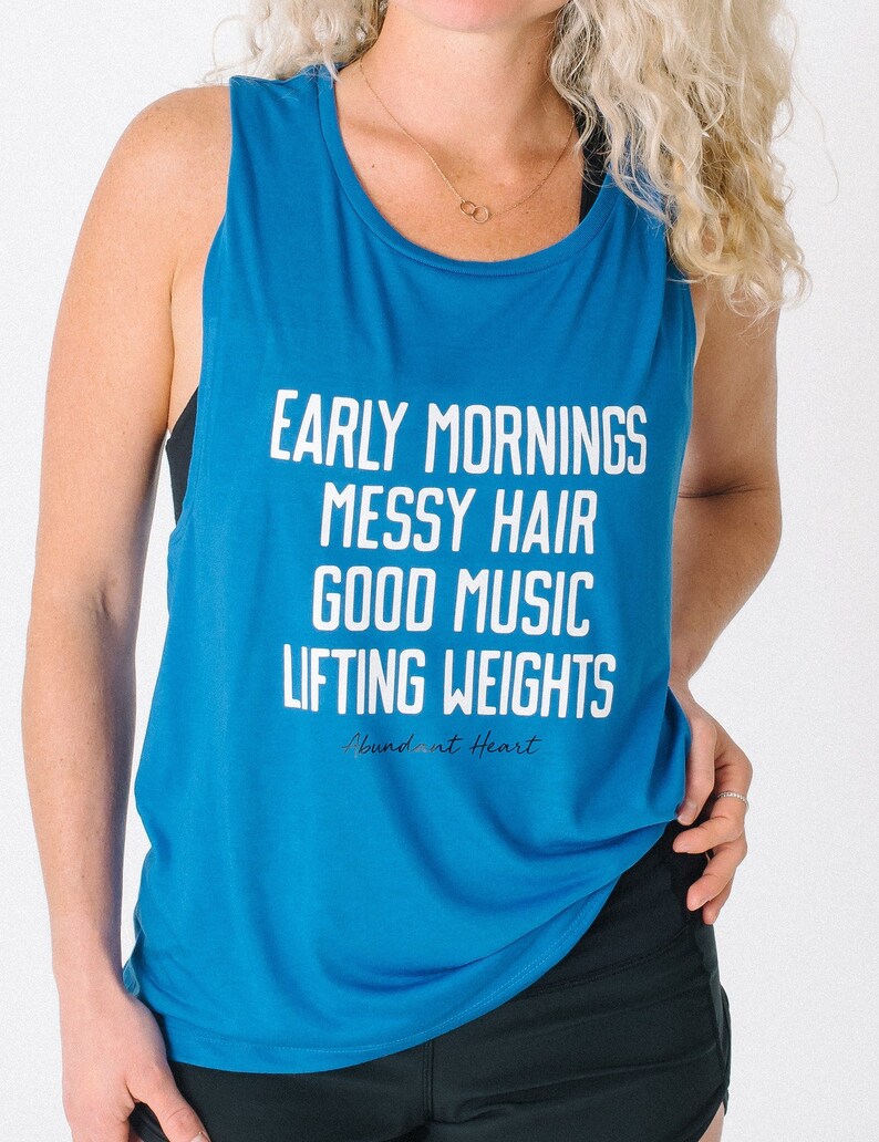 May include: A royal blue tank top with the text "Early Mornings Messy Hair Good Music Lifting Weights" and the logo "Abundant at Heart" in white.