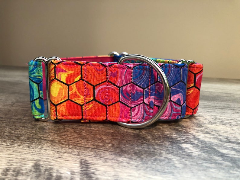 K&ouml;nnte beinhalten: Ein farbenfrohes Hundehalsband mit einem lebendigen, sechseckigen Muster in Orange, Pink, Blau und Gr&uuml;n. Das Halsband verf&uuml;gt &uuml;ber einen stabilen Metall-D-Ring und Beschl&auml;ge f&uuml;r den Leinenanschluss. Das Halsband ist auf Langlebigkeit und Stil ausgelegt.