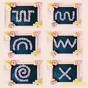 Könnte beinhalten: Ein Holzrahmen mit einer schwarzen Tafel im Inneren. Die Tafel hat verschiedene Buchstaben, die mit rosa Blumen ausgeschrieben sind. Die Buchstaben sind "YOU", "NOW", "W" und "X".