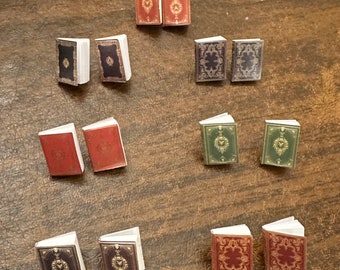 May include: Ten miniature books with decorative covers. The books are arranged in two rows of five. The covers are a mix of red, green, and black with gold accents.