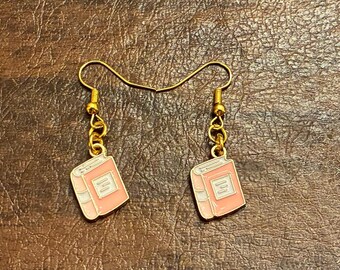 May include: Three pairs of gold dangle earrings with book charms. The charms are green, pink, and blue.