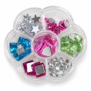 May include: A clear, flower-shaped plastic organizer container divided into six compartments. It is filled with assorted decorative craft gems in various shapes and colors, including silver stars, pink hearts, blue squares, green ovals, and clear round rhinestones.