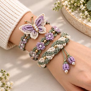 Puede incluir: Un conjunto de tres pulseras con elementos de ganchillo en tonos lavanda, verde salvia y crema. Los diseños incluyen un motivo de mariposa, pequeños patrones florales y texturas trenzadas, adornados con cuentas doradas y perlas blancas.