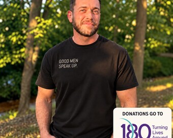 May include: A black short-sleeved t-shirt featuring the white text "GOOD MEN SPEAK UP." on the chest. The shirt is paired with blue denim jeans. A white square graphic in the corner displays "DONATIONS GO TO 180 Turning Lives Around."
