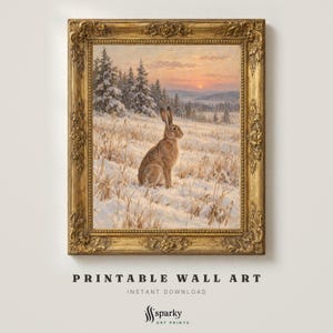 Puede incluir: Una impresión de arte mural enmarcada que muestra una liebre marrón sentada en un campo nevado al atardecer. El paisaje incluye árboles de hoja perenne y un cielo naranja suave. La obra está en un marco dorado ornamentado con tallas.