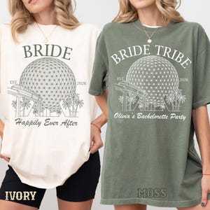 Puede incluir: Una camiseta color marfil con un gráfico verde oscuro de un domo geodésico, monorraíl y palmeras, con el texto "BRIDE", "EST. 2026" y "Happily Ever After". Una camiseta verde musgo con un gráfico blanco del mismo diseño, texto "BRIDE TRIBE", "EST. 2026" y "Olivia's Bachelorette Party".