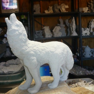 May include: White ceramic sculpture of a wolf howling at the moon. The sculpture is detailed with fur and has a realistic appearance.