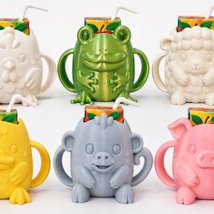 May include: Six animal-shaped juice box holders with two side handles each. The holders are white, metallic green, cream, yellow, gray, and pink. Each holder contains a rectangular juice box with a white straw inserted into the top opening.