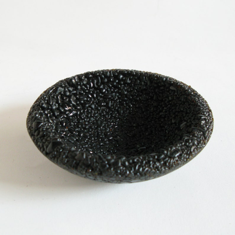 May include: A small, black ceramic bowl with a textured, bumpy surface.