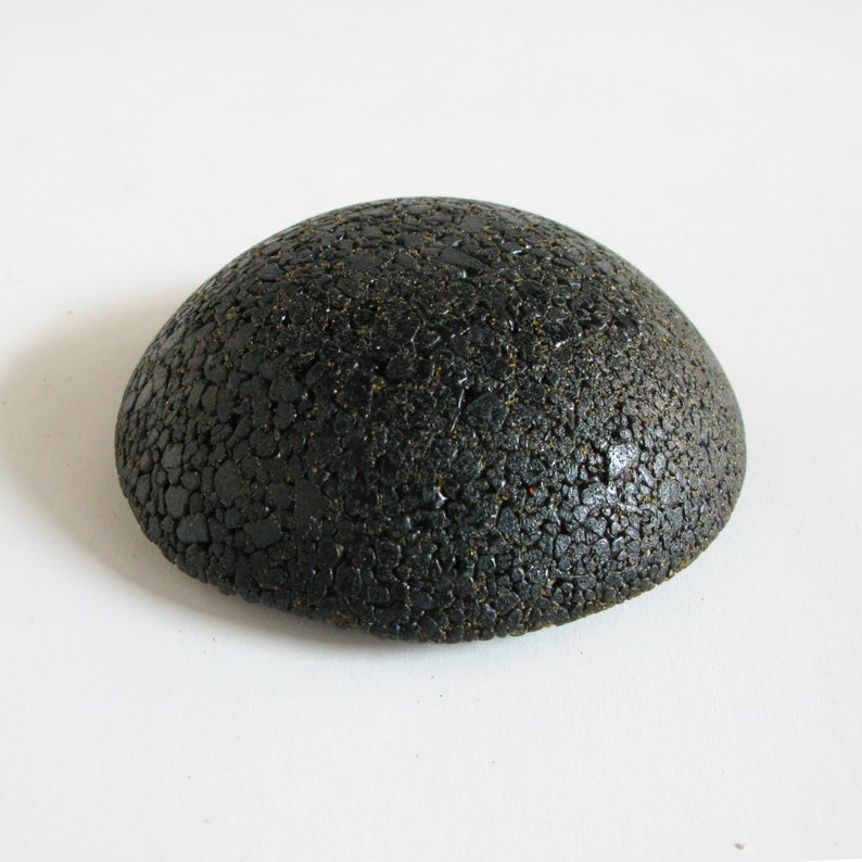 May include: A black, round, textured, dome-shaped object. The object is made of small, black, pebble-like pieces.