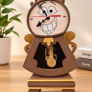 Peut inclure: Une horloge de cheminée marron et beige avec un visage de dessin animé au large sourire sur le cadran. L'horloge possède des aiguilles noires, une trotteuse rouge et un pendule visible à travers une ouverture centrale sur une base dorée.