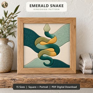 May include: A square wooden frame containing a Kinuasaiga fabric art piece featuring an emerald snake design. The snake is composed of interlocking fabric segments in shades of dark green, light green, and yellow, set against a cream background.