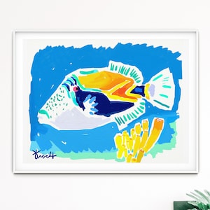 May include: A framed illustration of a colorful fish with a yellow, orange, and blue body swimming in blue water. The fish is surrounded by yellow coral. The artist's signature is in the bottom left corner.