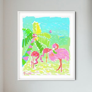 May include: A framed illustration of pink flamingos standing in a tropical setting with a palm tree and blue water. The artwork is in a white frame and is hanging on a white wall.