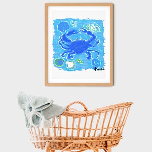 May include: A framed illustration of a blue crab with green and blue shells and seaweed on a light blue background. The artist's signature is in the bottom right corner.