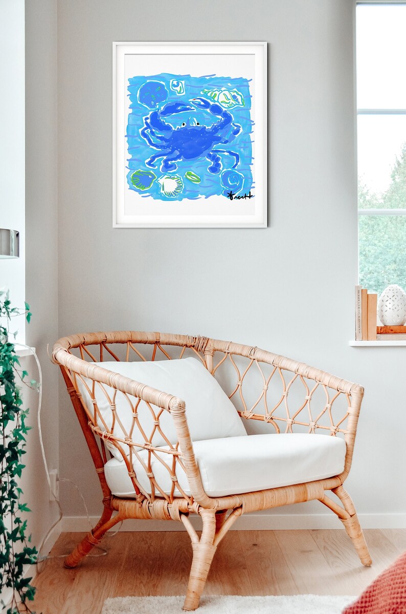 May include: A framed illustration of a blue crab with green and white seashells on a blue background. The artist's signature is in the bottom right corner.