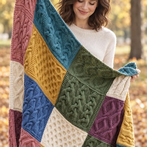 May include: A multi-colored knit blanket featuring a patchwork design of various textured cable and honeycomb patterns. The blanket is composed of square panels in shades of dusty pink, mustard yellow, teal, olive green, blue, and deep purple.
